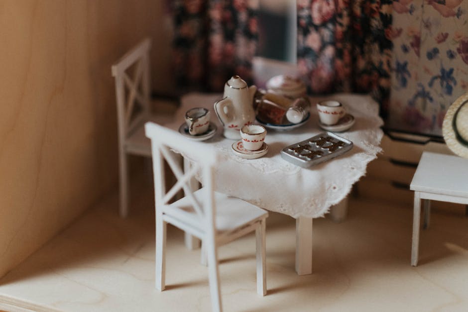 Charming miniature dollhouse dining room with an elegant tea set on a laced tablecloth.