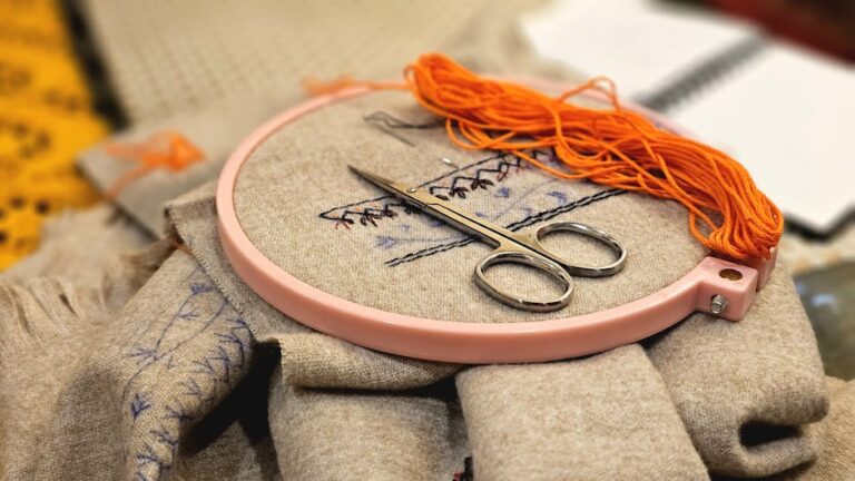 A detailed embroidery setup featuring scissors and thread in a pink hoop.