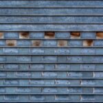 Close-up of a textured metal garage door with a unique brick-like pattern and weathered surface.