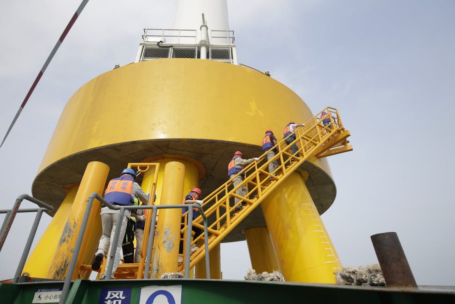 Workers in safety gear ascending a yellow industrial structure via a ladder.