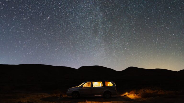 A peaceful desert scene with a glowing car under a vast starlit sky.
