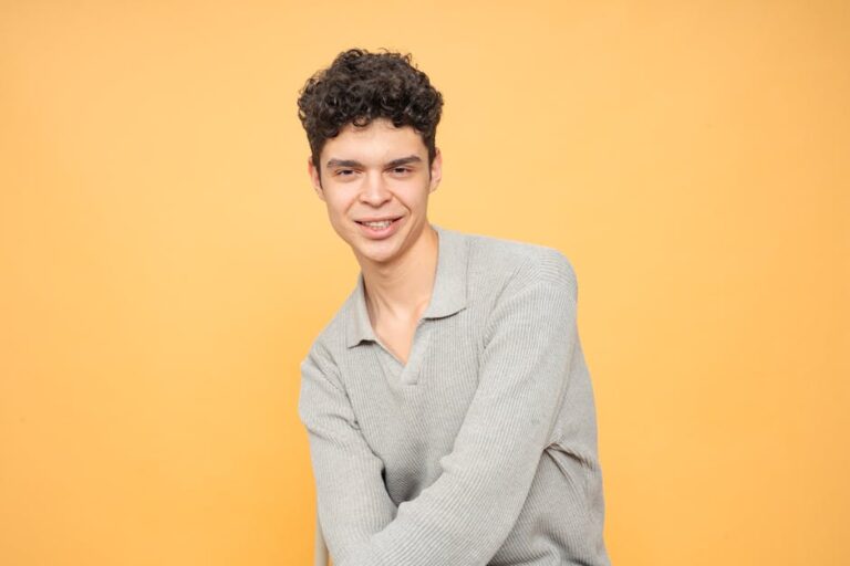 Portrait of a young man smiling in a studio with a yellow background.