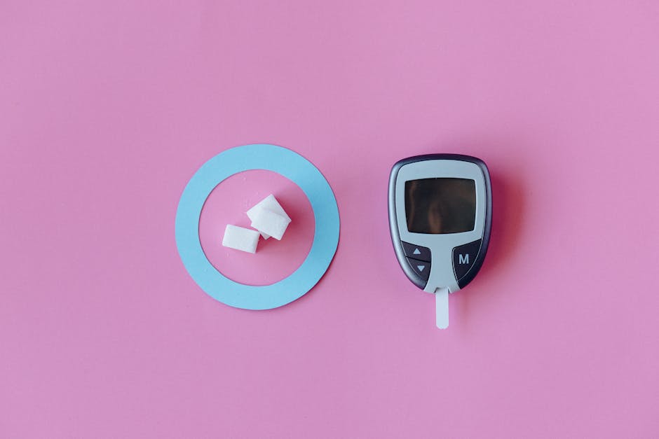 Flat lay of glucometer with sugar cubes on pink background, symbolizing diabetes awareness.