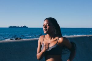 A woman jogging along the seaside, embodying a healthy lifestyle and enjoying an outdoor workout.