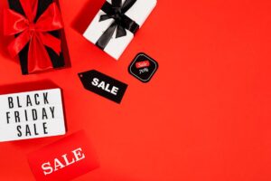 Flatlay of Black Friday sale gifts and tags on a red background with ample copy space.
