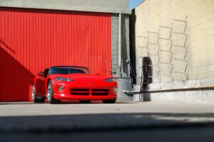 A vibrant red sports car parked by a red garage door, showcasing sleek automotive design.