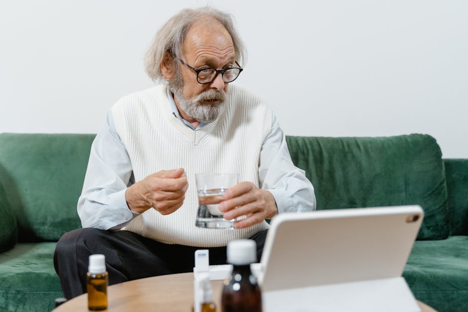 Senior man consulting doctor online, holding medicine and glass indoors.