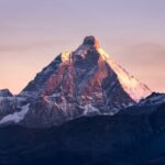 Stunning view of the Matterhorn mountain illuminated by the first light of sunrise against a colorful sky.