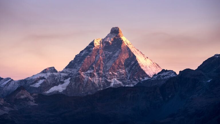 Stunning view of the Matterhorn mountain illuminated by the first light of sunrise against a colorful sky.