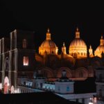 Stunning nighttime view of the illuminated Cuenca Cathedral, showcasing its iconic architecture under a starlit sky.