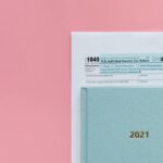 U.S. 1040 tax form with 2021 planner on a pastel pink background, symbolizing tax season.