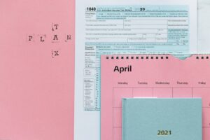 Tax-related items on a pink background, including forms and a calendar.