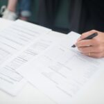Close-up of a hand signing insurance documents in an office setting.
