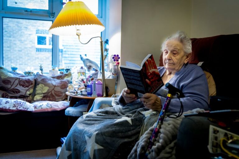 Elderly woman enjoying a book in a cozy living room, embracing retirement leisure time.