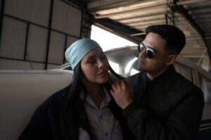A couple standing in a hangar beside a small airplane.