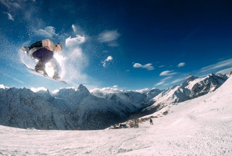 Snowboarder performing a high jump in a picturesque snow-covered mountain landscape during the day.