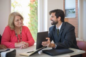 Elderly woman consulting with a realtor about a property deal in a cozy indoor setting.